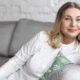 Εμμηνόπαυση. Η εικόνα δείχνει μια κυρία ηλικίας μεταξύ 50 και 60 ετών καθισμένη σε καναπέ φορώντας λευκά ρούχα